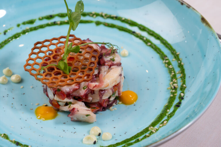 Entrée de saison dressée sur assiette, coulis vert et tuile croustillante